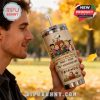 Man drinking from Peanuts tumbler outdoors in fall setting.