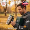 Man outdoors holding Eagles mug and gift box with fall leaves.