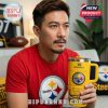 A man watching football at home while holding a Steelers Stanley tumbler, surrounded by Pittsburgh Steelers merchandise.