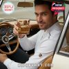 A man inside a classic Porsche car holds a detailed Porsche 95th Anniversary glass filled with whiskey, showing off its elegant golden design!