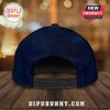 Back view of a dark blue snapback hat on a wooden surface.!