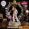 Elvis Presley statue with a flower frame and golden top sphere, on a wooden table.!