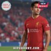 Red Liverpool F.C. soccer jersey with sponsor logos and yellow swoosh, displayed on a model.!