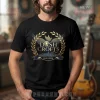 Black t-shirt displays a gold and blue memorial design, flying dove, olive wreath! Text: DASH CROFTS IN LOVING MEMORY 1940-2026!