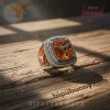 Ornate silver collegiate ring featuring large orange gem, prominent silver longhorn logo, clear stone accents, and text 