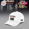 White baseball cap with The Strokes Reality Awaits The World 2026 tour logo in black and red text with a band silhouette!