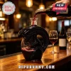 Black glass alien xenomorph shaped wine decanter on a wooden bar with red wine being poured from a bottle!