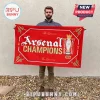 Red rectangular Arsenal Champions 25/26 flag with gold cannons and Premier League trophy graphic on white background!