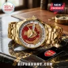 Gold Arsenal FC watch with red dial, crest, and 2025-26 season text on a marble surface.!