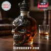 Decorative glass whiskey decanter shaped like a skull with ornate metal filigree and crown stopper on a wooden table!