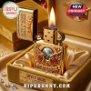 Gold ornate Guns N' Roses lighter with flame, featuring revolvers, red roses,