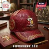 Red leather baseball cap with gold Kappa Alpha Psi Greek letters and fraternity crest on a desk.!
