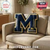 Blue and yellow letter M throw pillow shaped like a football with Michigan Wolverines text and logo on a couch!