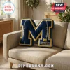 Blue and yellow M-shaped plush pillow featuring Michigan Wolverines logo and football stitching on couch!