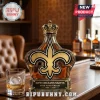 Glass liquor bottle with gold crown cap and New Orleans Saints fleur-de-lis logo for 60th anniversary 1966-2026!