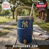 A textured blue New York Yankees commemorative water cooler with a gold logo and spigot on a wooden picnic table next to peanuts and a team scarf in a park!