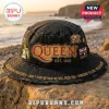 Black distressed Queen band bucket hat featuring red gold QUEEN EST 1970 text, Freddie Mercury, band crest, Union Jack patch, and song titles around the brim!