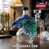 Clear glass decanter shaped like a blue and green eagle head on a wooden table!