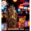 Steampunk style liquor bottle with brass gears and pipes on a bar counter next to an amber cocktail glass!