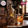 Steampunk style metal liquor bottle with bronze gears and tubing design next to a glass of whiskey on a wooden desk!