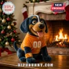 Plush dog toy in orange jersey with letter T and 00 wearing orange wristband sitting on table in front of fireplace!