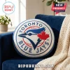Round white throw pillow with embroidered Toronto Blue Jays baseball team logo in blue and red on blue sofa!