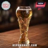 Clear glass beer mug shaped like a soccer trophy filled with golden lager, sitting on a wooden bar top.!
