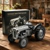 Gray plastic building block model of a vintage tractor next to its black cardboard retail box on a rustic wooden table.!