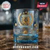 Blue tinted glass whiskey tumbler featuring gold AFA logo, three stars, soccer balls, stadium, and Messi graphic art.!