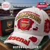 White distressed Arsenal FC baseball cap with gold Champions lettering and UEFA Champions League patch on green surface.!