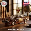 Amber glass Batmobile whiskey decanter with gold crown stopper, sitting on a wooden desk with blurred library background.!