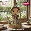 Beatrix Potter vinyl figure holding a Peter Rabbit doll and a book on a decorative display base near a window.!