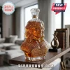 Glass bust decanter shaped like a woman filled with amber liquor, featuring a diamond-cut stopper and etched gold text.!