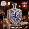 Crystal whiskey decanter featuring a blue lion crest shield design, set on a dark wood bar with a glass and cigar.!