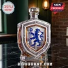 Crystal shield-shaped whiskey decanter featuring a blue lion emblem on a black marble table in a bar setting.!