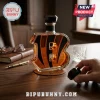 Glass whiskey decanter shaped like the Cincinnati Bengals B logo filled with amber liquid on a leather coaster.!