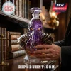 Purple faceted glass octopus decanter with gold armor details on a wooden library table with smoke emitting from the top.!