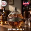 Death Star shaped glass whiskey decanter with metallic Imperial emblem and textured surface on a wooden table.!