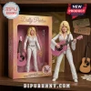 Dolly Parton collectible action figure in white rhinestone jumpsuit holding a pink guitar with packaging box on wood shelf.!