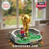 Brick-built FIFA World Cup 2026 gold trophy model with a soccer player minifigure on a green field and stadium base.!