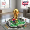 Gold FIFA World Cup trophy Lego model with a soccer player minifigure on a green pitch base inside a stadium display.!