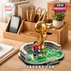 Gold FIFA World Cup 2026 building block trophy on a green stadium base with a miniature soccer player figurine.!