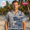 Man wearing short-sleeve button-down shirt with blue and white vintage Ford Mustang car graphics and text on a beach.!