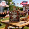 Generation X themed whiskey bottle with metallic label reading Fuck Your Feelings, 1965-1980, on a wooden picnic table.!