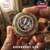 Gold Grateful Dead commemorative ring featuring an iridescent central skull, clear stones, and colored side gems.!