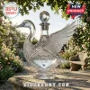 Crystal swan-shaped vodka decanter on a stone pedestal with diamond-cut patterns and a sphere stopper in a garden setting.!
