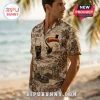 Man wearing a cream-colored short-sleeve button-down shirt featuring a vintage Guinness toucan and brewery print on a beach.!