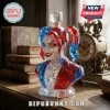 Harley Quinn bust glass decanter with faceted red and blue hair and heart-shaped stopper on a wooden desk with old books.!
