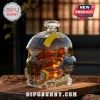 Helldivers 2 themed glass decanter shaped like a soldier helmet filled with amber liquid on a rustic wooden table.!