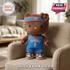 Brown Hello Kitty plush doll wearing an Oklahoma City Thunder jersey, shorts, headband, and sneakers on a beige chair.!